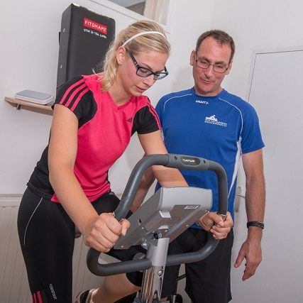 sportmasseur en vrouw op hometrainer